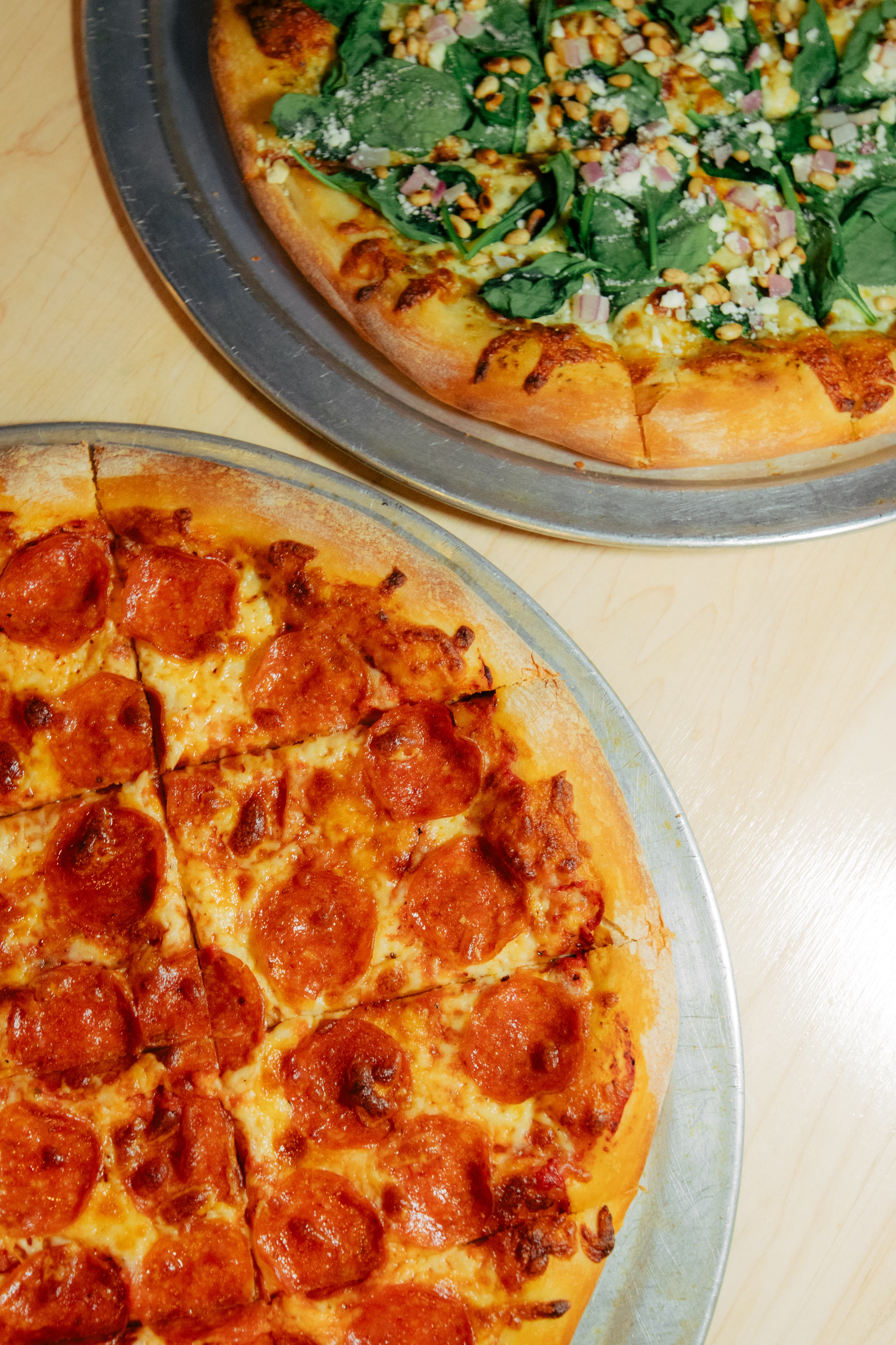 Two stone-fired pizzas at Harper's East Lansing  pepperoni and spinach pesto sharing the table