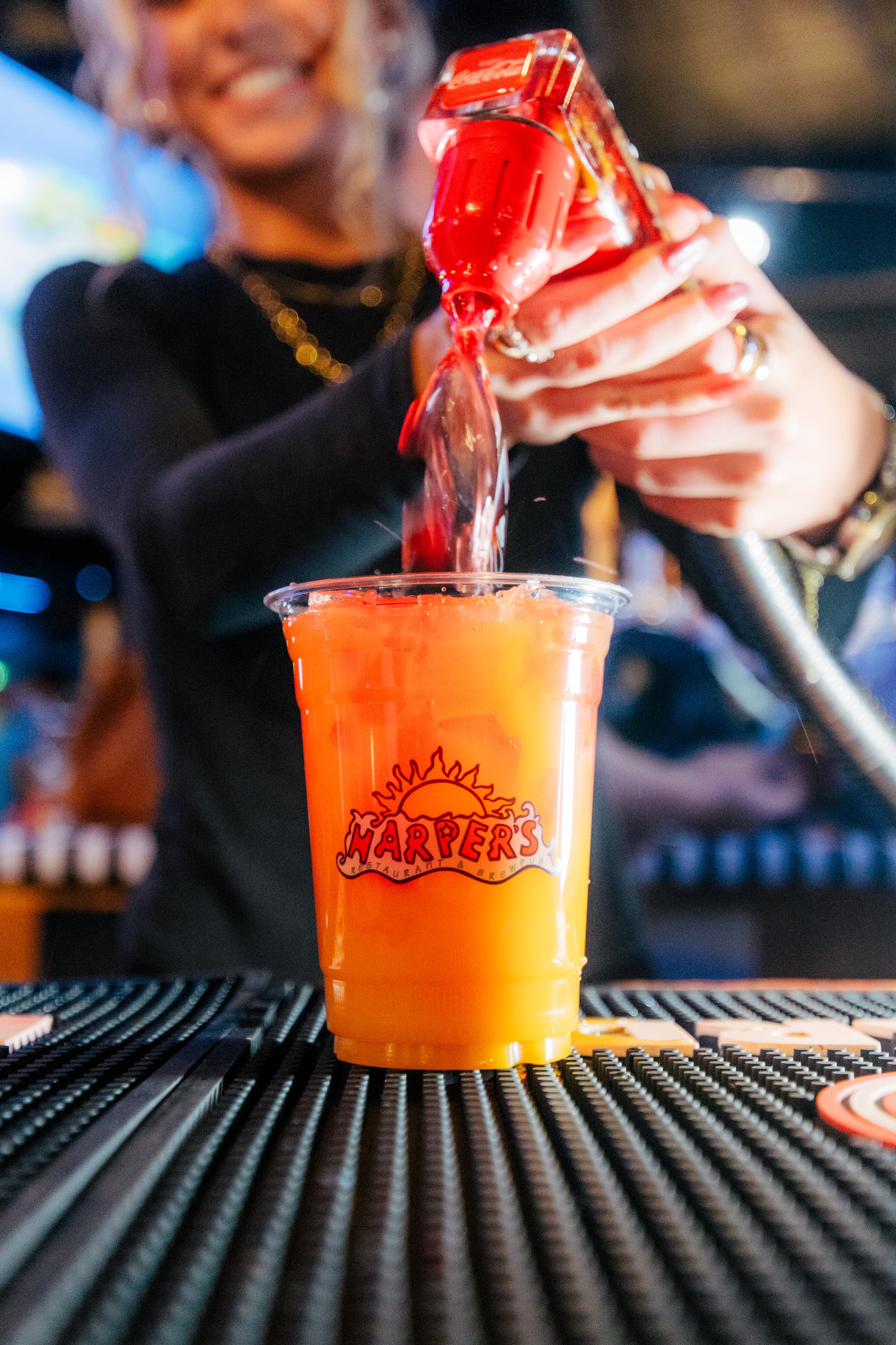 Bartender at Harper's East Lansing pouring a signature drink  Cat's Pajamas and Gypsy Vodka on the menu